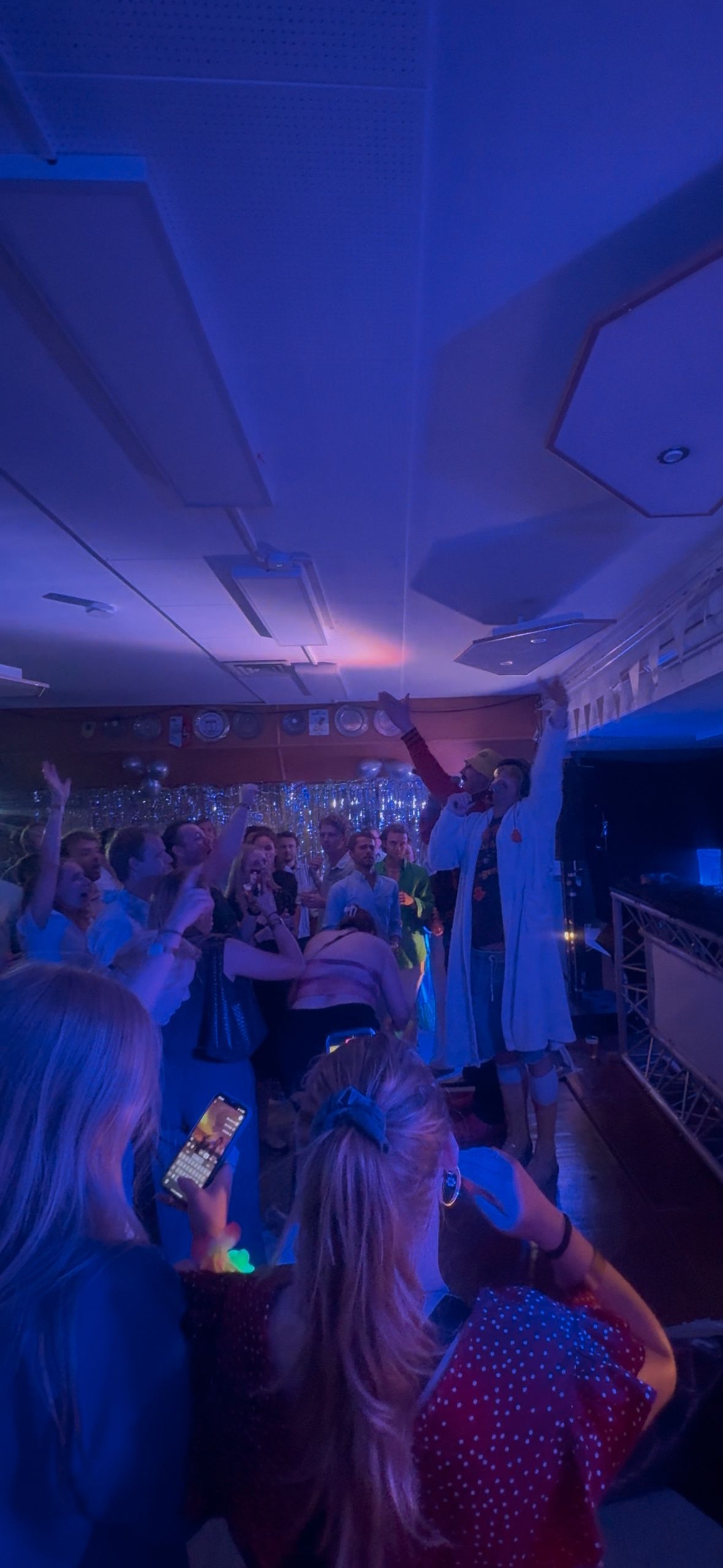 Artiesten en gasten tijdens het feest onder blauwe verlichting
